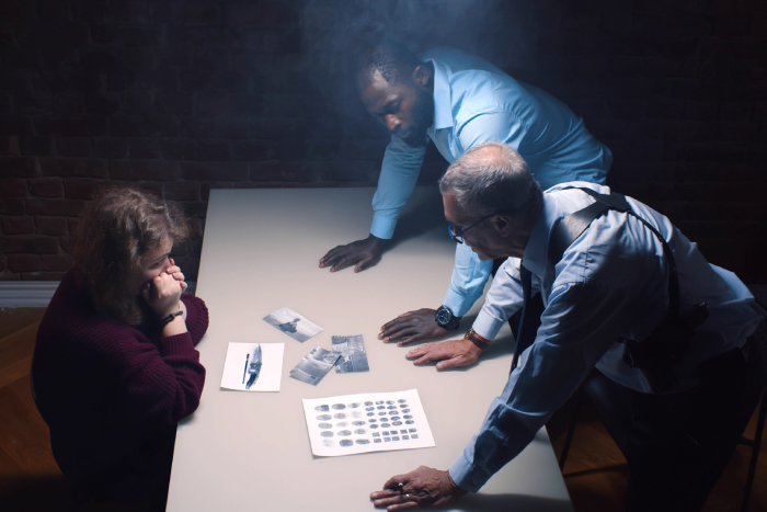 Diverse detective interrogating scared arrested woman