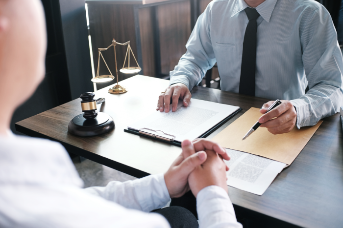 Legal counsel presents to the client a signed contract with gavel and legal law.