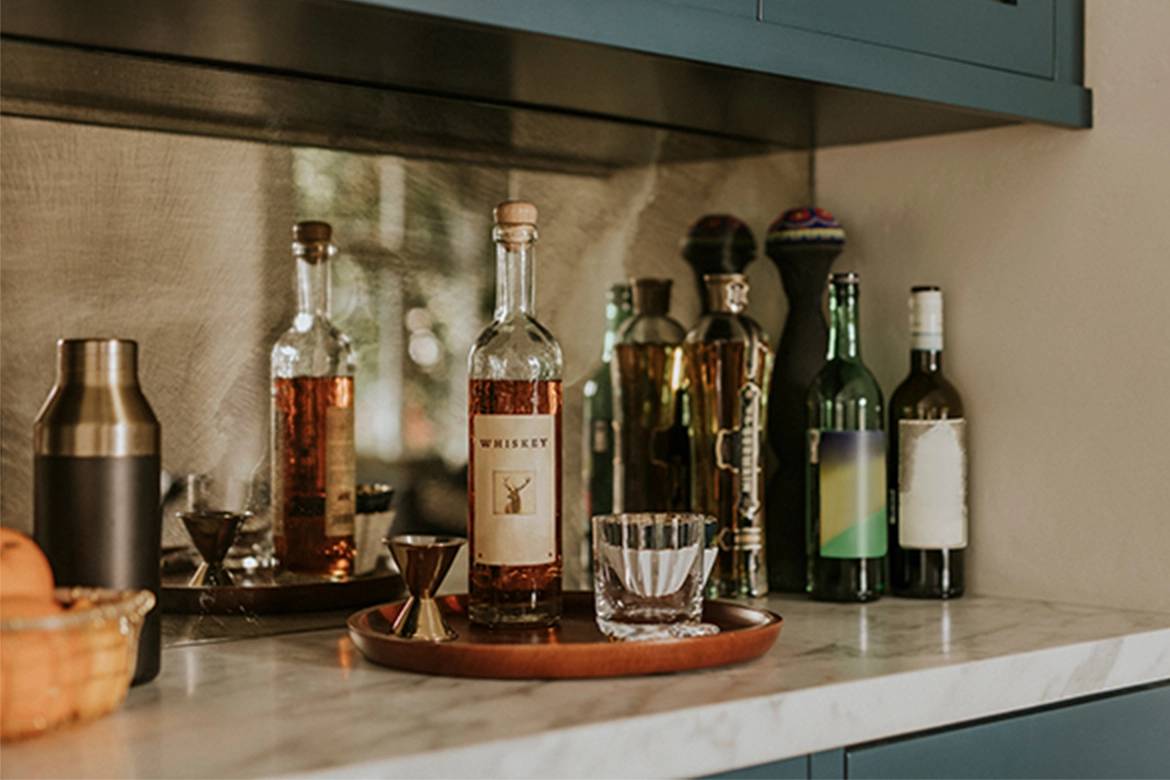A bottle of whiskey and several other liquor placed on a wooden tray.