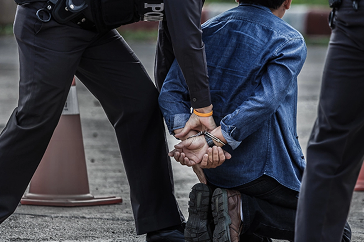 A person's hand are handcuffed behind his back and being arrested.